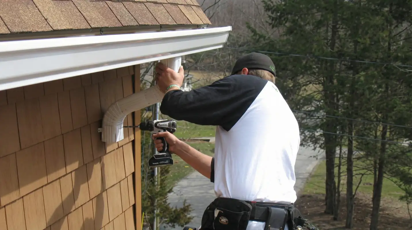 Professional contractor installing tan vinyl siding panels on a residential home exterior in ,